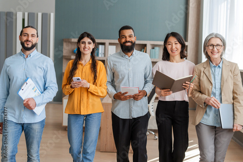 Diverse business team walking together in modern office, looking at camera