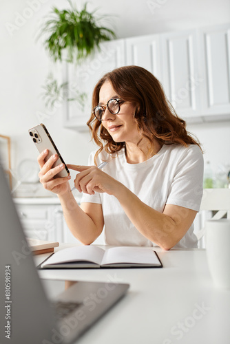 Middle-aged woman engrossed in her cellphone at a table.