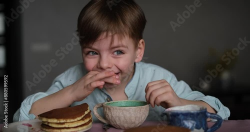 Little adorable boy drinking tea for breakfast with pancakes and apples at home. Cute weekend with sweet tasty food and emotional child. video footage 4k