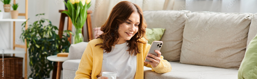 Middle aged woman sits on couch, engrossed in cellphone. Middle aged woman sits on couch, engrossed in cellphone.