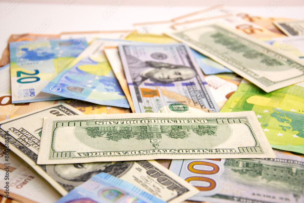 A close-up photograph showing a collection of US Dollar and Euro banknotes strewn across a white surface A close-up photograph showing a collection of US Dollar and Euro banknotes strewn across a white surface