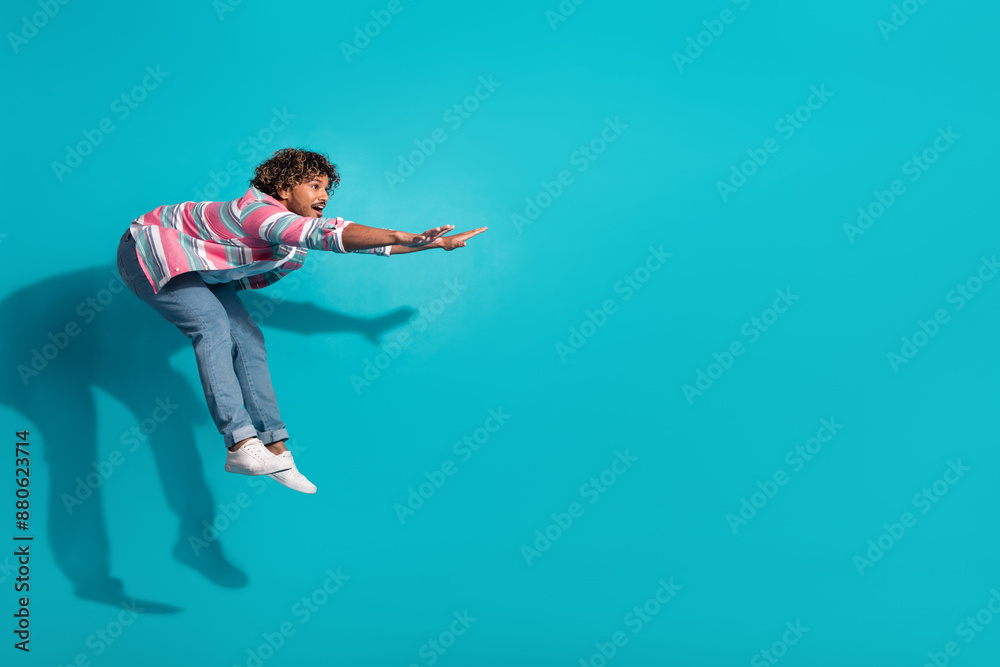 Obraz premium Photo of positive crazy man wear trendy striped clothes fly air empty space isolated on cyan color background