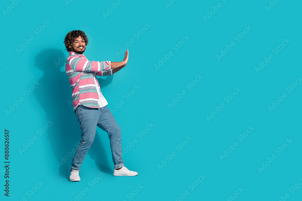 Photo of cheerful nice funny man wear trendy striped clothes hold empty space isolated on cyan color background Photo of cheerful nice funny man wear trendy striped clothes hold empty space isolated on cyan color background