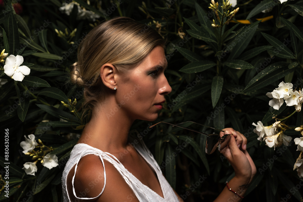 Beautiful woman in a white dress posing on the leaves backdrop. Fashion concept. Hard light. Beautiful woman in a white dress posing on the leaves backdrop. Fashion concept. Hard light.