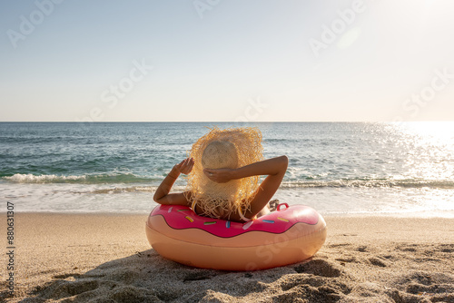 Happy woman with inflatable donut on a tropical beach. Summer vacation concept.