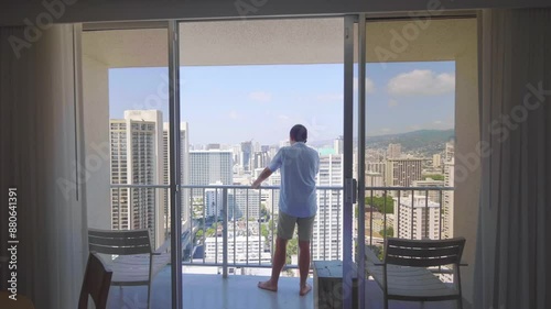 Man talking on the phone and admiring the view of Honolulu city in Hawaii from a balcony in 4k slow motion 60fps