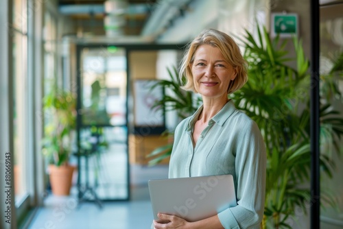 Smiling Woman Holding Laptop in Modern Office - Business Success Concept