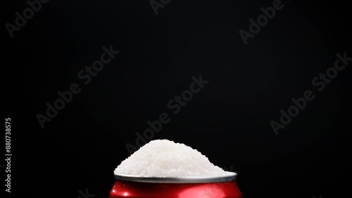 A can of soda with white sugar poured onto a black background, showing an example of how harmful sugar is and how we all eat too much sugar in a healthy eating concept.