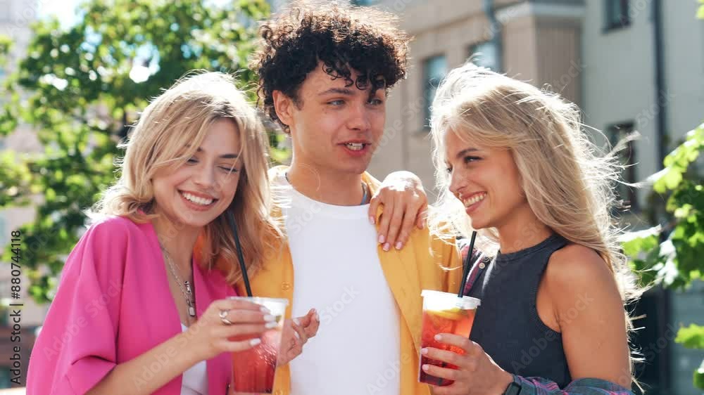 Young three stylish friends posing in the street. Fashion man and two cute female dressed in casual summer clothes. Smiling models having fun. Cheerful women and guy outdoors, Hold and drink lemonade Young three stylish friends posing in the street. Fashion man and two cute female dressed in casual summer clothes. Smiling models having fun. Cheerful women and guy outdoors, Hold and drink lemonade