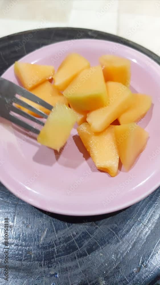 Sliced Ripe Melon Pieces Resting Beside a Fork on a Pink Plate Sliced Ripe Melon Pieces Resting Beside a Fork on a Pink Plate