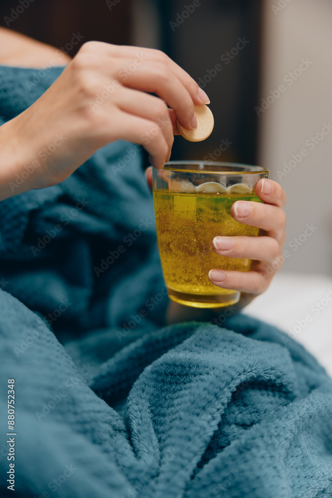 Woman in a blue blanket holding a cup of green tea while sitting on a bed with pillows Woman in a blue blanket holding a cup of green tea while sitting on a bed with pillows