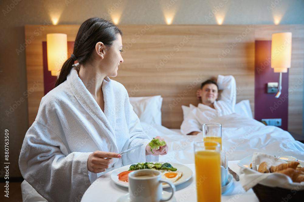 Female having breakfast in suite in presence of her companion Female having breakfast in suite in presence of her companion
