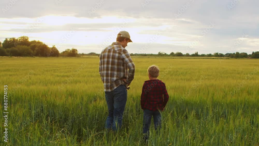 Farmer and his son in front of a sunset agricultural landscape. Man and a boy in a countryside field. Fatherhood, country life, farming and country lifestyle concept. Farmer and his son in front of a sunset agricultural landscape. Man and a boy in a countryside field. Fatherhood, country life, farming and country lifestyle concept.