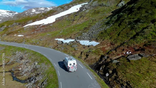 Camper van travels through a scenic mountain road in spring, surrounded by snow and greenery. A perfect travel escape. Langvatnet, Geiranger, Norway photo