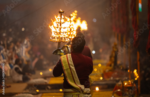 Ganga aarti, Portrait of young priest performing holy river ganges evening aarti at assi ghat in traditional dress with hindu rituals