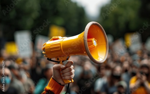 A yellow megaphone held up in front of a crowd of people at a protest or rally.  The focus is on the megaphone.