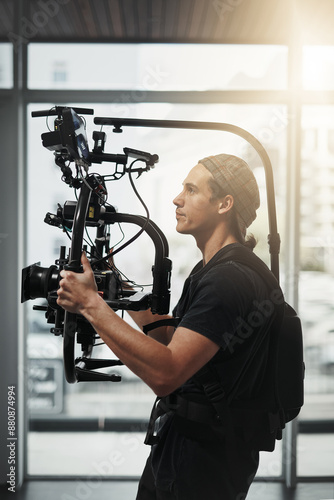Photographer, camera and photography with stabilizing rig on set for filming, media and magazine. Cameraman, focus and person backstage for shooting, production and film as director with equipment