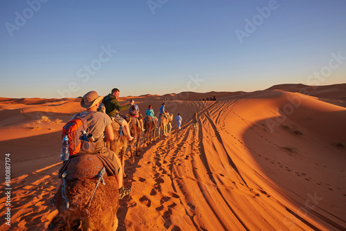 Tourists riding camels, smiling, in the Sahara Desert