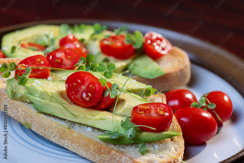 A slice of toasted sour dough bread with avocado and tomato on top A slice of toasted sour dough bread with avocado and tomato on top