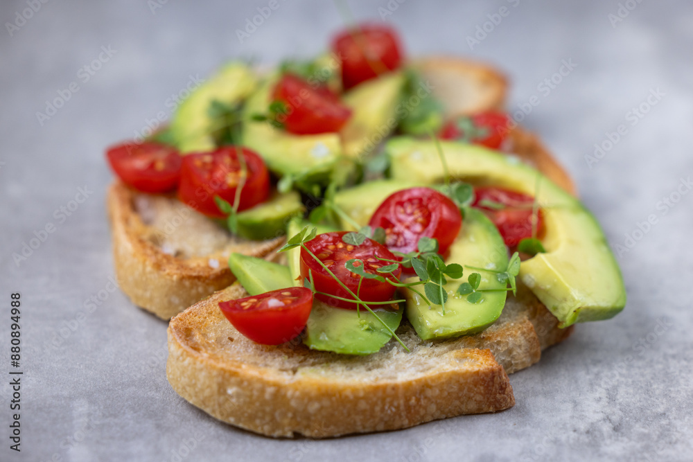 A slice of toasted sour dough bread with avocado and tomato on top A slice of toasted sour dough bread with avocado and tomato on top
