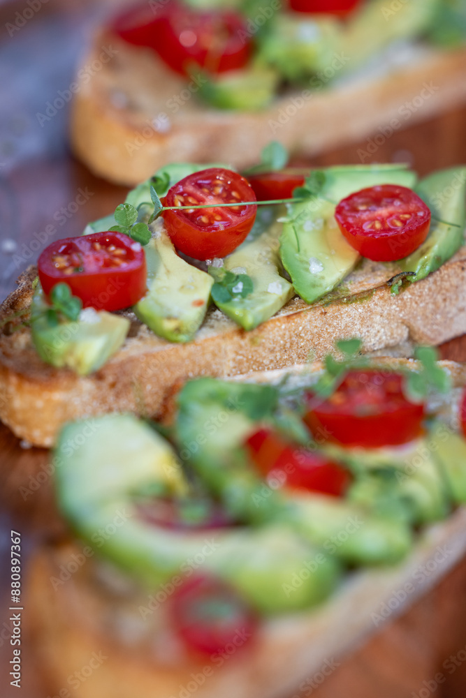 A slice of toasted sour dough bread with avocado and tomato on top A slice of toasted sour dough bread with avocado and tomato on top