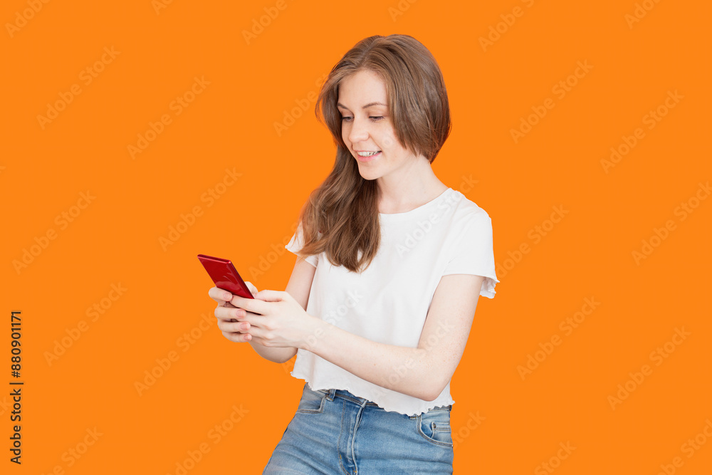 Smiling woman using smartphone on orange background Smiling woman using smartphone on orange background