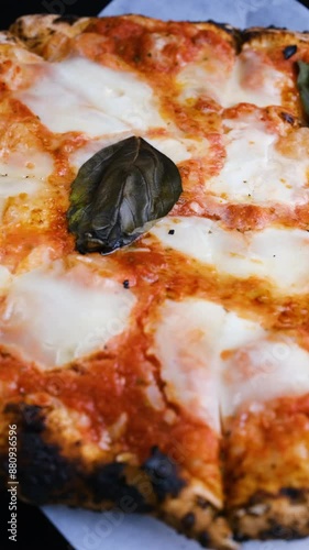 Close-up, Margherita pizza with melted mozzarella cheese spinning in a circle. Vertical video. Fresh delicious food. Pizza Margherita. Italian Cuisine.