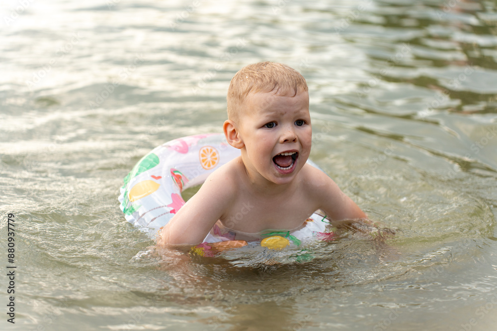 Child is afraid to swim in the water. Little boy playing in the water with a swimming ring on a sunny day at the beach. High quality photo Child is afraid to swim in the water. Little boy playing in the water with a swimming ring on a sunny day at the beach. High quality photo