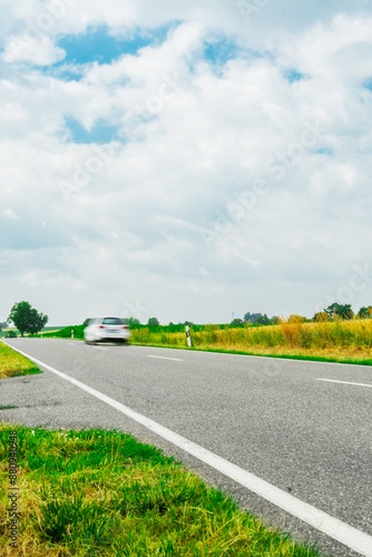 Fast White Car Driving along a Lonly Road in the Farm Field with Motion Blur photo