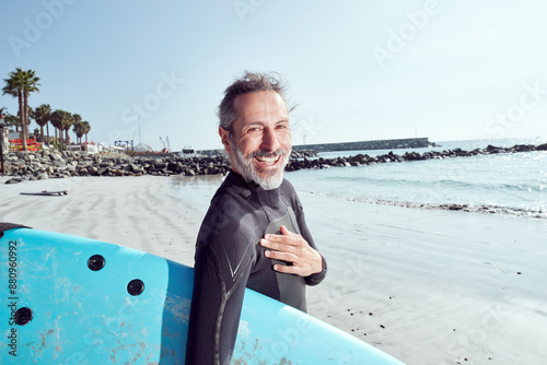 Photography portrait happy mature surfer man on the beach holding a surfboard