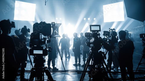 A professional studio set for a commercial video, with lighting equipment, crew members, and silhouettes behind the camera.