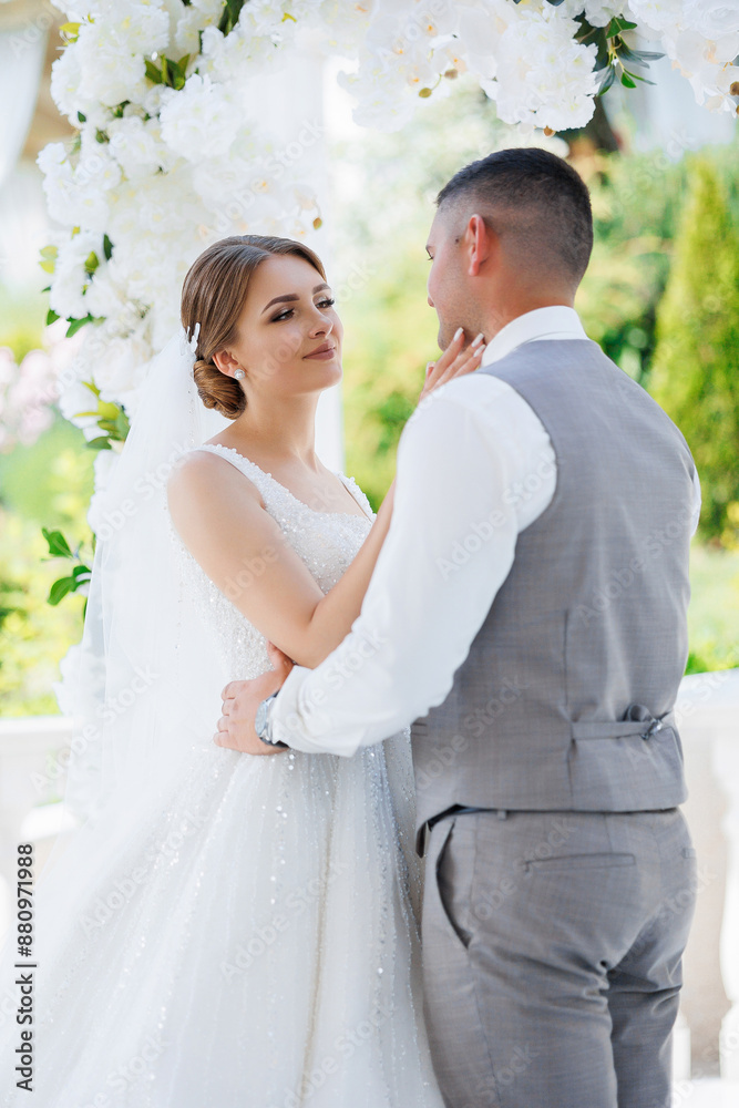 A bride and groom are embracing each other in a wedding ceremony. The bride is wearing a white dress and the groom is wearing a gray vest. The scene is filled with love A bride and groom are embracing each other in a wedding ceremony. The bride is wearing a white dress and the groom is wearing a gray vest. The scene is filled with love