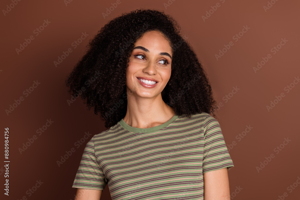 Photo of charming positive girl wear striped t-shirt smiling looking empty space isolated brown color background Photo of charming positive girl wear striped t-shirt smiling looking empty space isolated brown color background