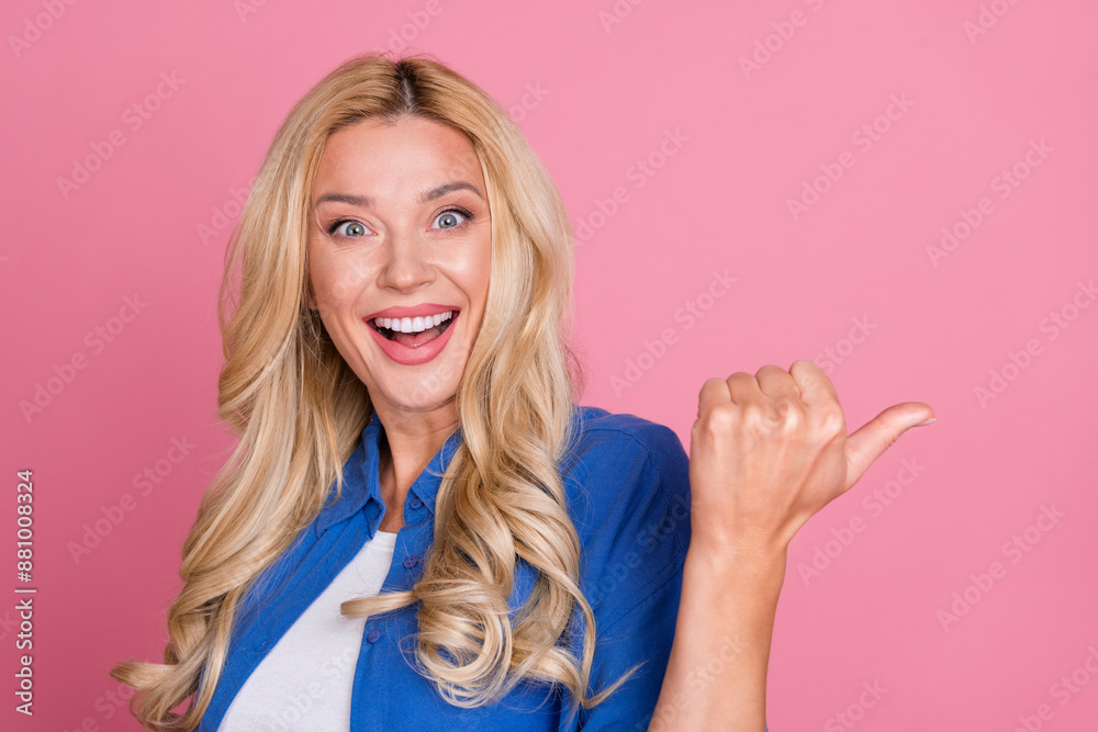 Obraz premium Photo of adorable excited woman wear blue shirt pointing thumb back empty space isolated pink color background