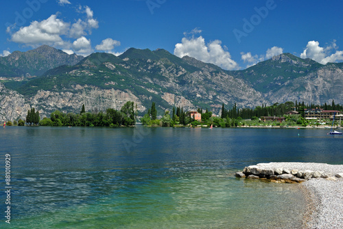 View of Lake on Sunny Day with Mountains Shoreline and Deserted Rocky Beach