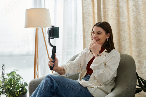 A young woman vlogs about her day, laughing while filming with a phone stabilizer. photo