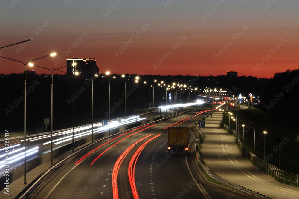 View of streaks of light from cars against a red sunset background View of streaks of light from cars against a red sunset background