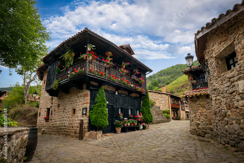 Typical street of the medieval town of Bárcena Mayor, Cantabria, Spain, with flowers on its wooden balconies and stone paving