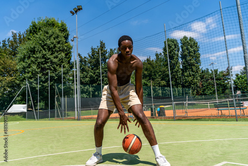 young african american athlete basketball player in action dribbling on artificial grass playing field on a sunny summer day outdoors