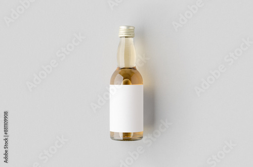 Miniature spirits, liquor bottle mockup. Clear glass, amber liquid with a blank label. photo