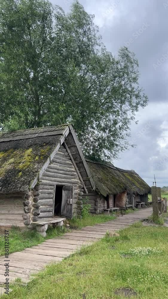 Rustic wooden cabins with mossy roofs nestled on a countryside path surrounded Rustic wooden cabins with mossy roofs nestled on a countryside path surrounded