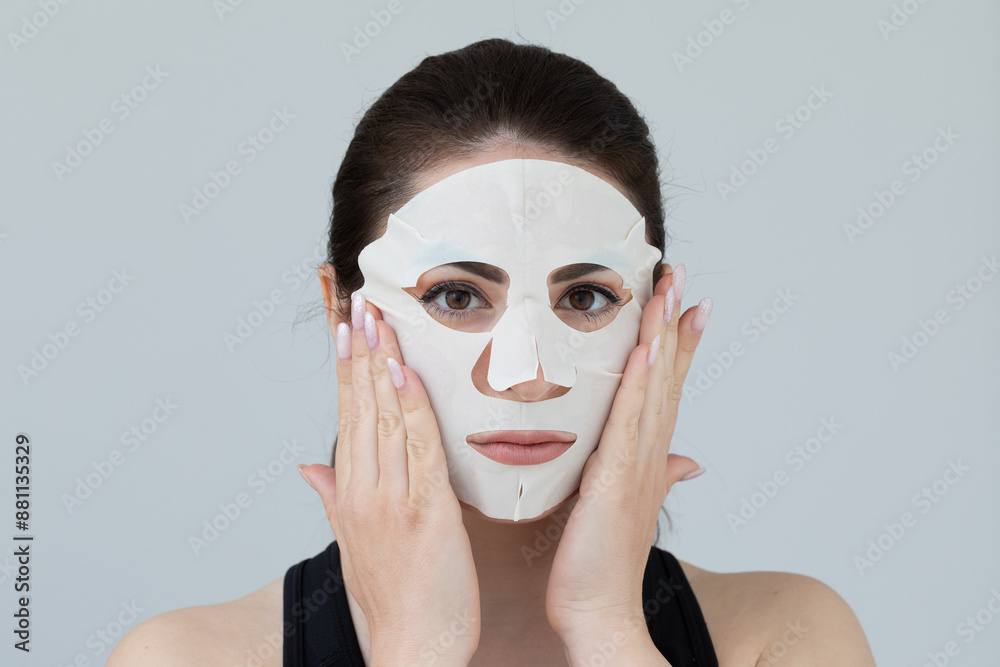 Beautiful young woman applying sheet mask on face Beautiful young woman applying sheet mask on face