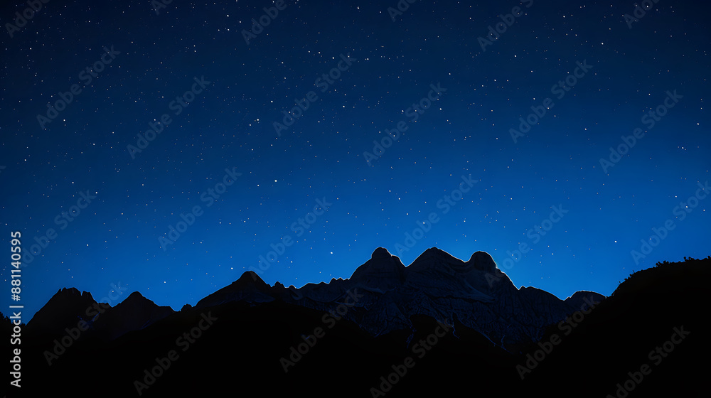 A mountain range is silhouetted against a dark sky with a few stars visible A mountain range is silhouetted against a dark sky with a few stars visible