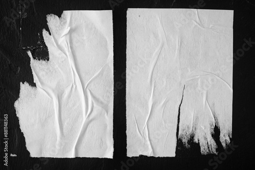 Two torn posters on a black wall.