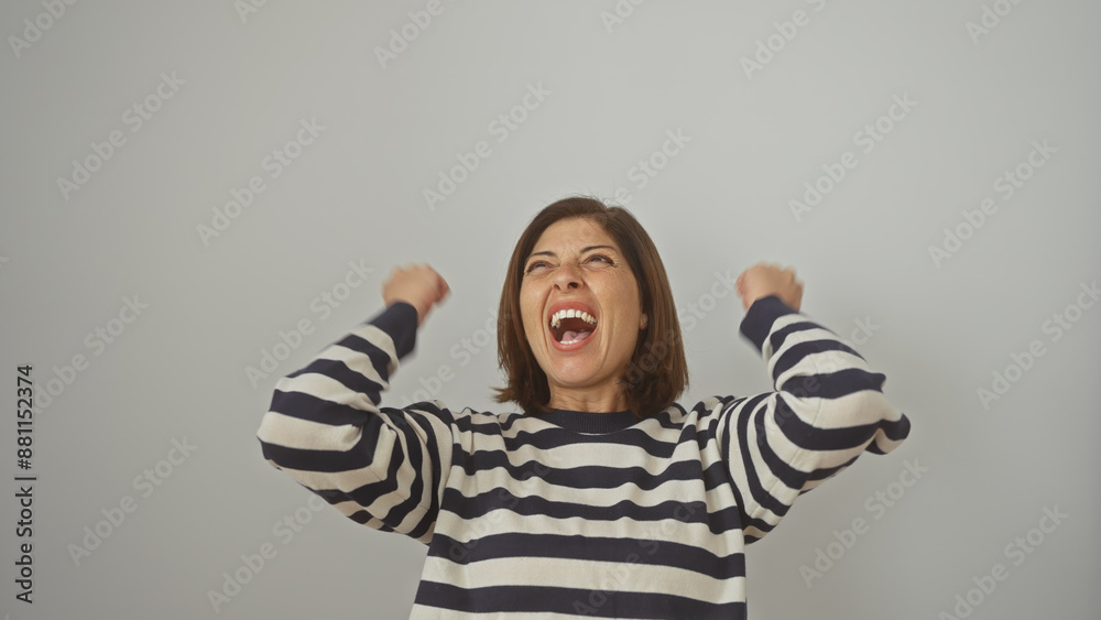 A jubilant hispanic middle-aged woman celebrates in a striped shirt against a white isolated background. A jubilant hispanic middle-aged woman celebrates in a striped shirt against a white isolated background.
