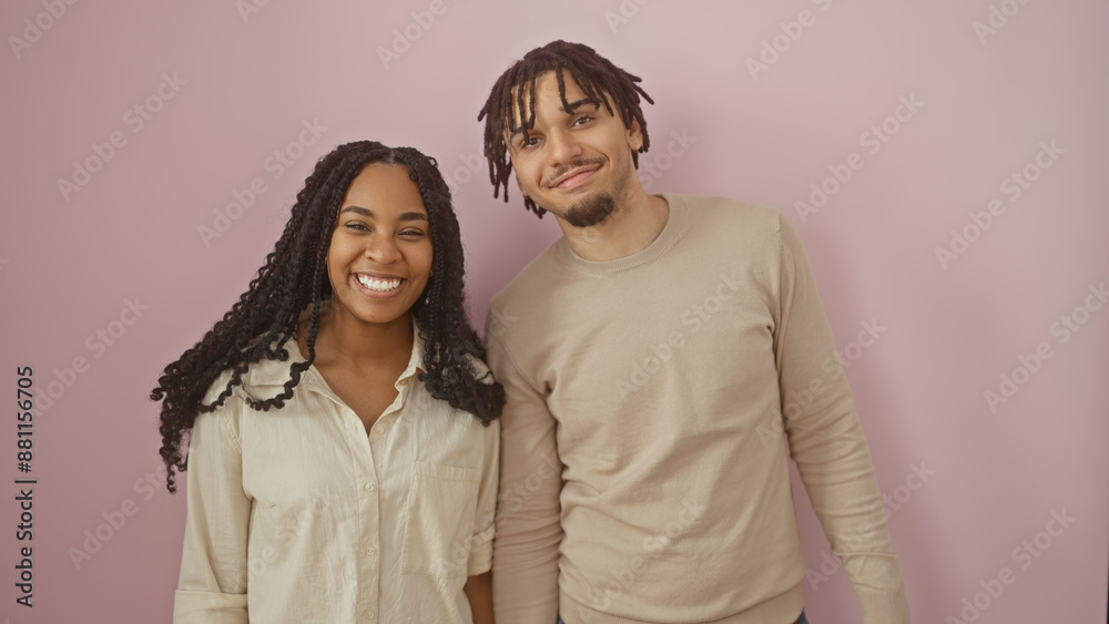 Smiling couple standing together against a pink background, embodying love and companionship. Smiling couple standing together against a pink background, embodying love and companionship.