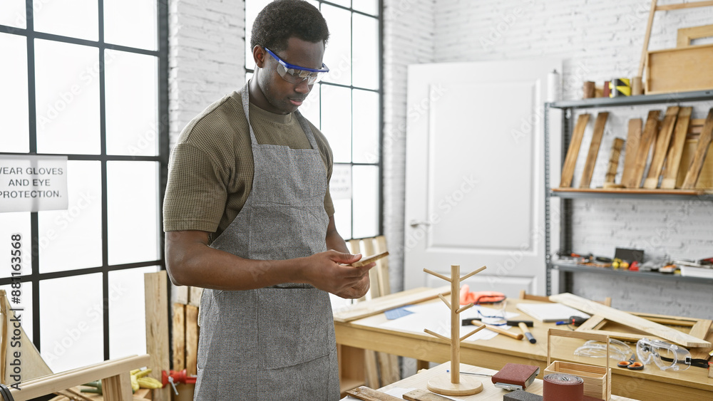 African american man using smartphone in carpentry workshop African american man using smartphone in carpentry workshop