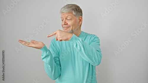 A mature man in a teal sweater points at invisible object against white background, exemplifying presentation skills. © Krakenimages.com