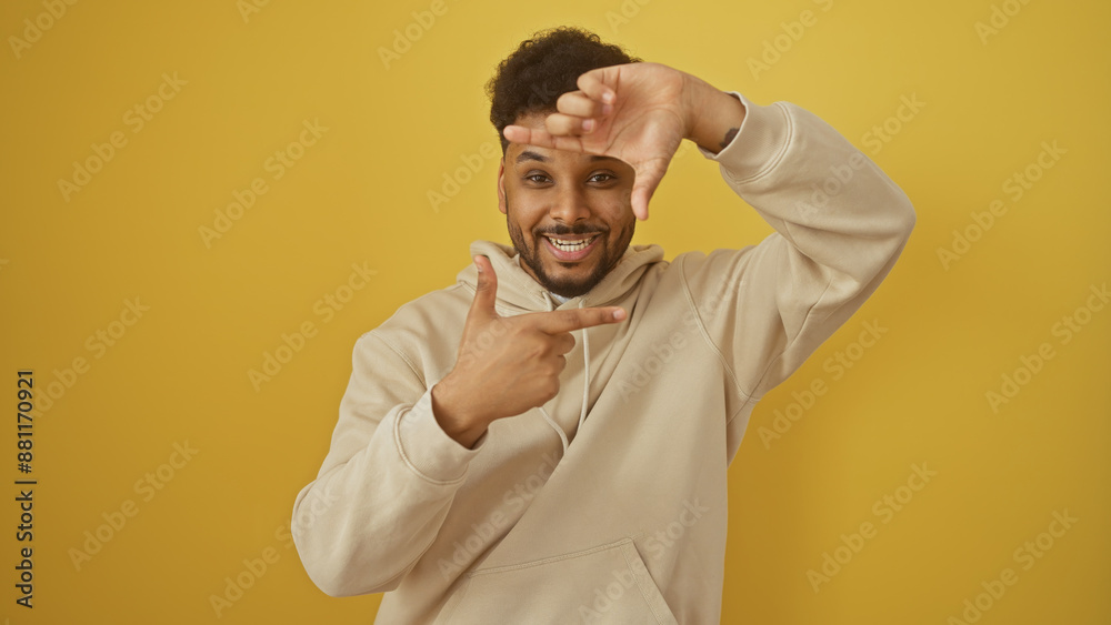 Obraz premium Cheerful man framing face with fingers against yellow background