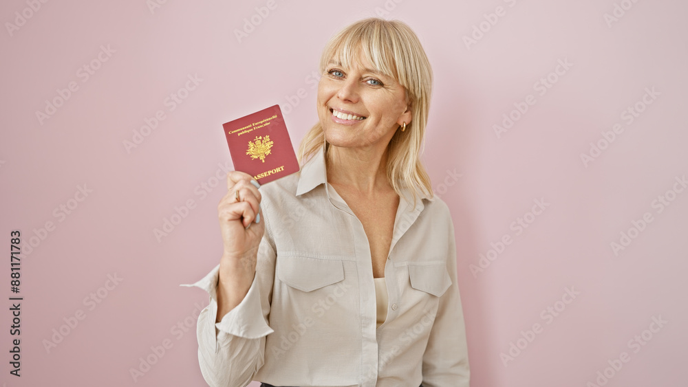 Smiling blonde woman in a beige shirt holding a french passport over a pink background, looking confident and ready to travel. Smiling blonde woman in a beige shirt holding a french passport over a pink background, looking confident and ready to travel.